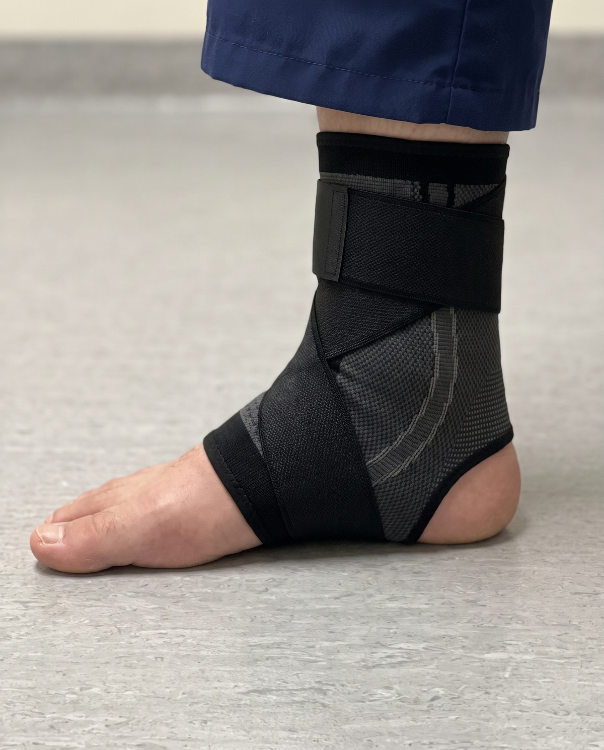 Kindheel arch-strap sleeve on a foot: the strap crosses the top of the foot, runs under the arch and wraps the ankle